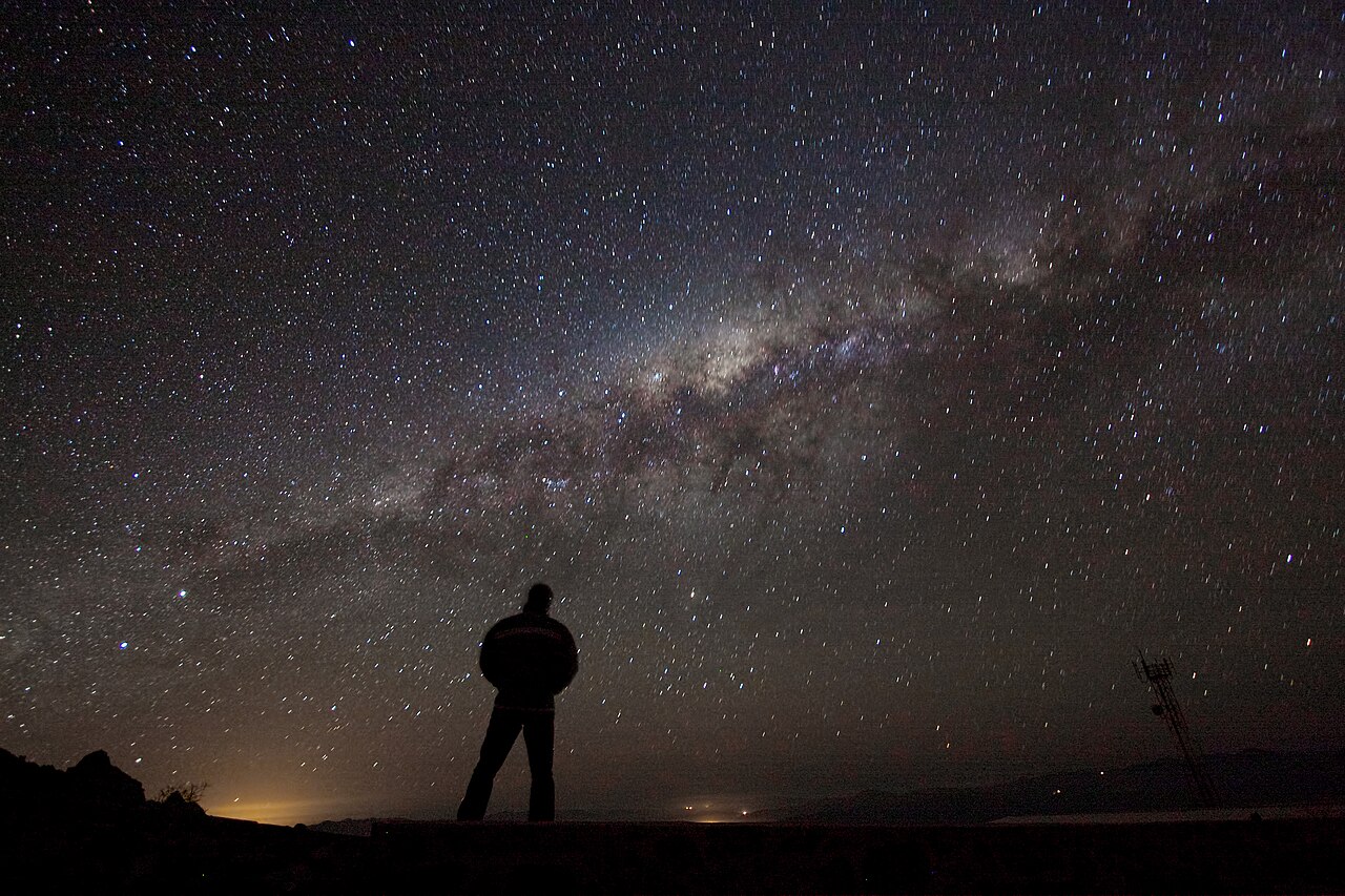 A stargazer with a telescope silhouetted against the Milky Way